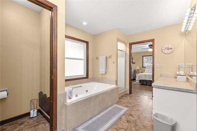 bathroom with a textured ceiling, tiled tub, and vanity