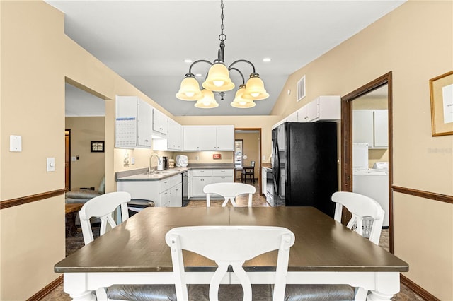 dining room with vaulted ceiling, a chandelier, washer and clothes dryer, and sink