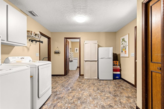 laundry area featuring independent washer and dryer, a textured ceiling, and cabinets