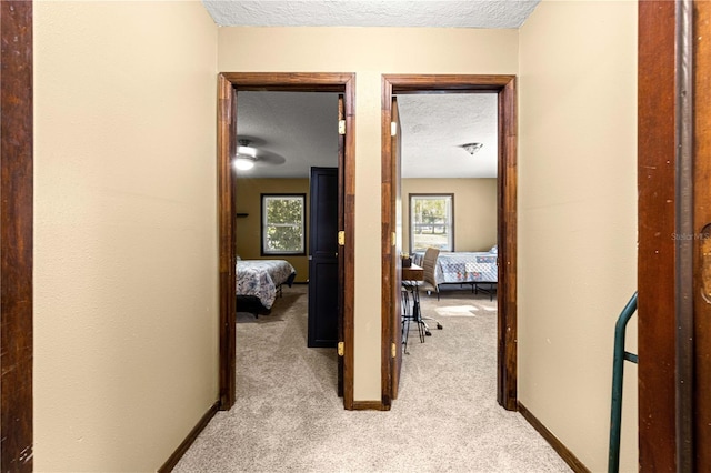 corridor featuring a textured ceiling and light carpet