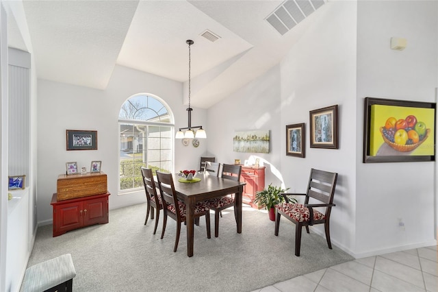 dining space with an inviting chandelier, lofted ceiling, and light tile patterned flooring