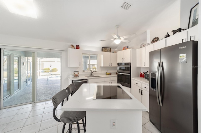 kitchen with white cabinets, appliances with stainless steel finishes, a kitchen island, and a kitchen breakfast bar