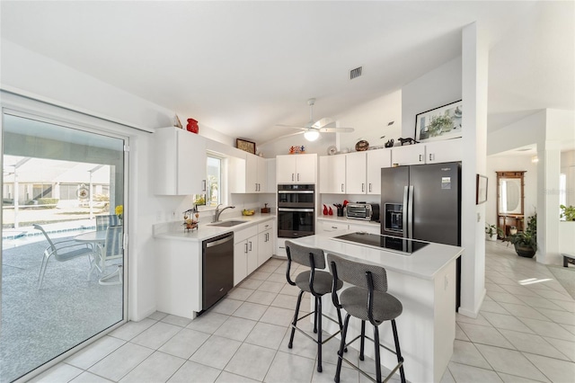 kitchen featuring light tile patterned flooring, a kitchen breakfast bar, a kitchen island, white cabinetry, and stainless steel appliances