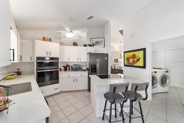 kitchen with white cabinets, a center island, appliances with stainless steel finishes, and washing machine and clothes dryer