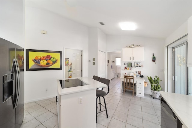 kitchen featuring appliances with stainless steel finishes, vaulted ceiling, light tile patterned floors, a center island, and white cabinetry