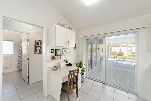 kitchen featuring white cabinets, light tile patterned flooring, and vaulted ceiling