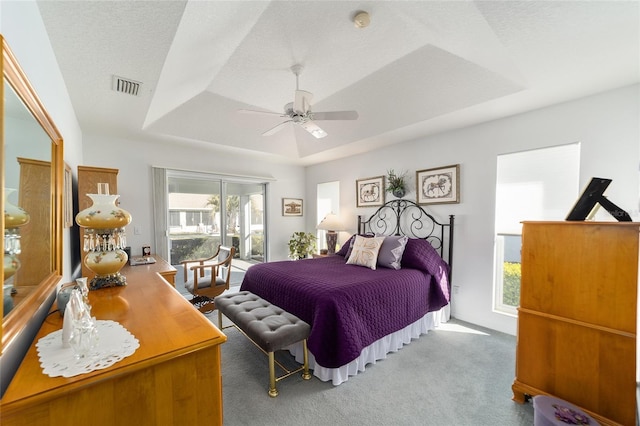 bedroom with light carpet, access to exterior, a textured ceiling, a raised ceiling, and ceiling fan