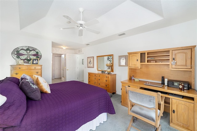 bedroom with ceiling fan, light carpet, and a tray ceiling