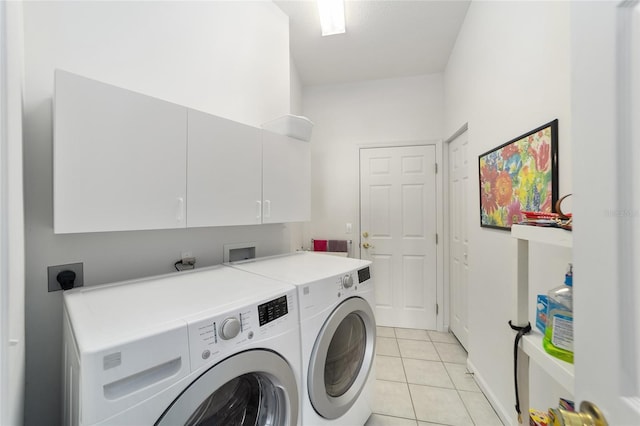 laundry area featuring washer and dryer, cabinets, and light tile patterned floors