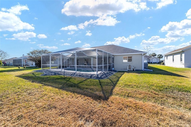 rear view of property featuring a lawn and glass enclosure