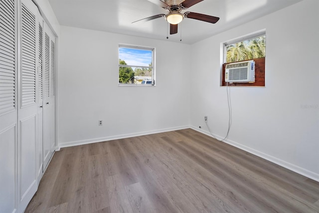 unfurnished bedroom featuring ceiling fan, cooling unit, light wood-type flooring, and a closet