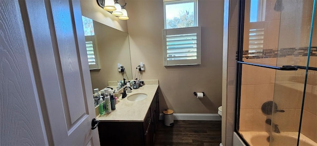 full bathroom featuring wood-type flooring, bath / shower combo with glass door, toilet, and vanity