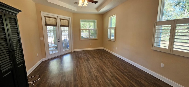 interior space with dark wood-type flooring, french doors, a tray ceiling, and ceiling fan