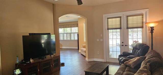 living area featuring baseboards, french doors, wood finished floors, arched walkways, and a ceiling fan