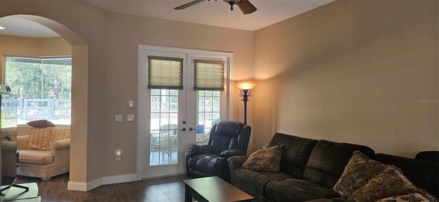 living area featuring a ceiling fan, dark wood-style floors, french doors, arched walkways, and baseboards