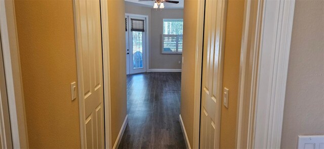 hall featuring dark wood-type flooring and baseboards