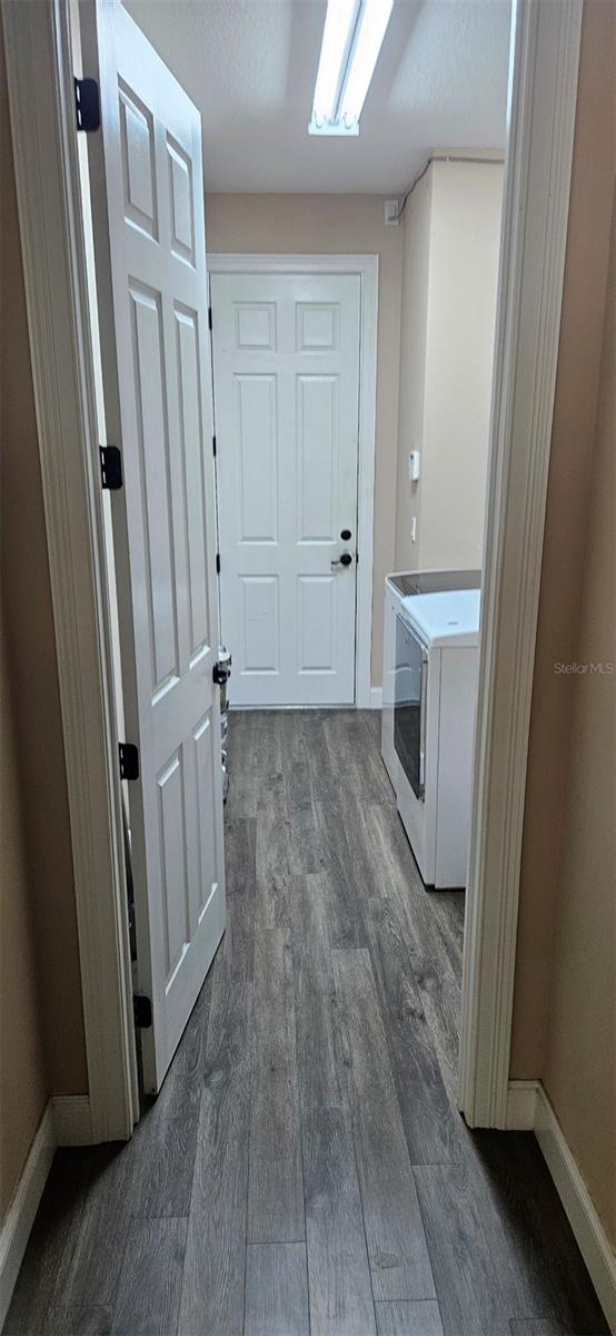 corridor with baseboards, dark wood-style flooring, and washing machine and clothes dryer