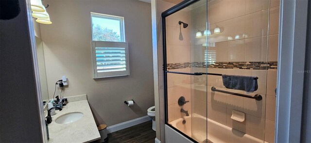 full bathroom with toilet, wood finished floors, combined bath / shower with glass door, baseboards, and vanity