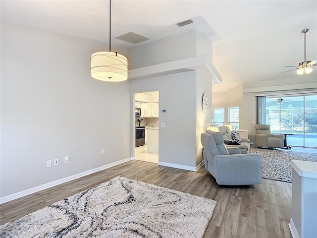 living room featuring vaulted ceiling, light hardwood / wood-style floors, and ceiling fan