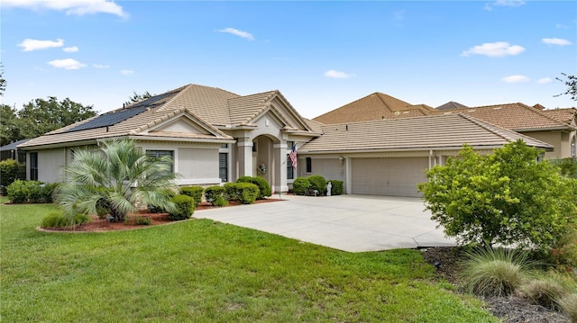 ranch-style home with solar panels, a garage, and a front yard