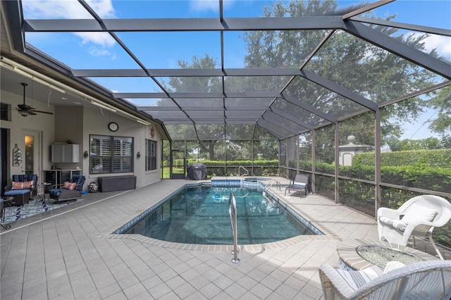 view of swimming pool featuring glass enclosure, ceiling fan, and a patio area