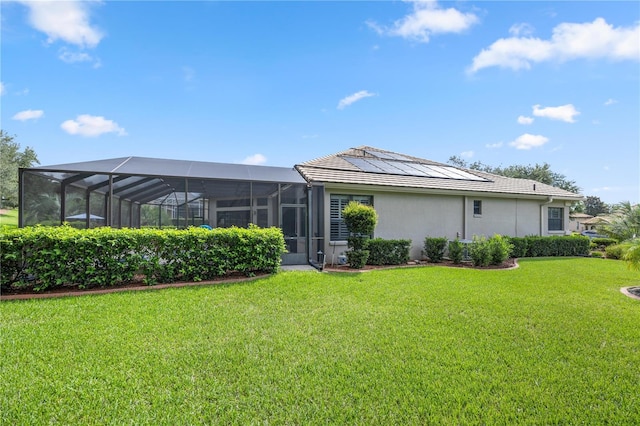 rear view of property with a lanai, a yard, and solar panels