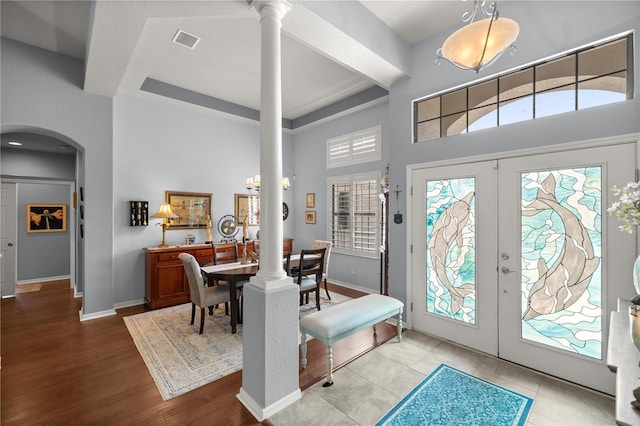 entrance foyer with ornate columns, french doors, and a high ceiling