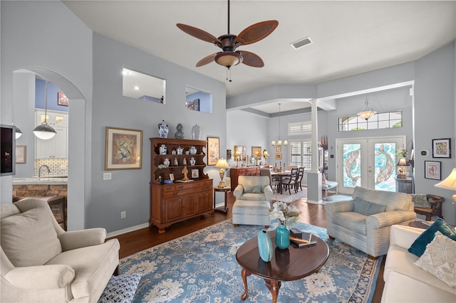 living room featuring french doors, a towering ceiling, ceiling fan with notable chandelier, dark wood-type flooring, and sink