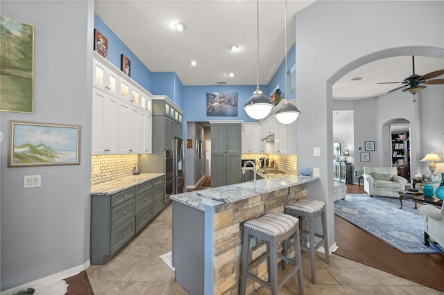 kitchen featuring kitchen peninsula, pendant lighting, tasteful backsplash, and white cabinetry