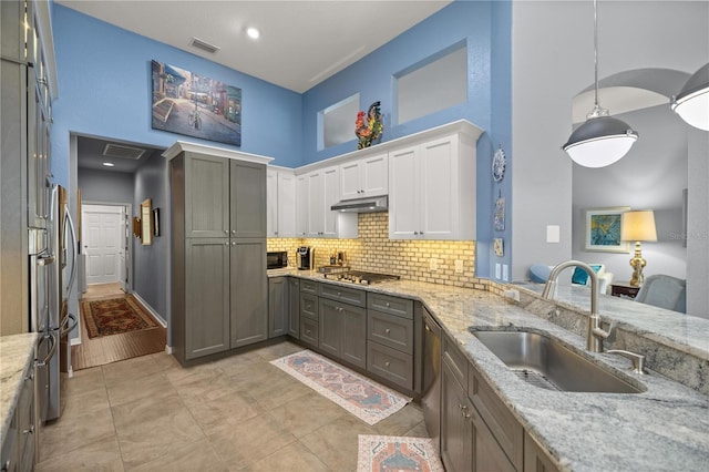 kitchen featuring pendant lighting, white cabinets, sink, decorative backsplash, and a towering ceiling