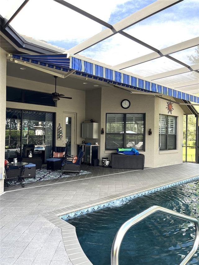 view of swimming pool featuring ceiling fan, an outdoor hangout area, a patio, and glass enclosure