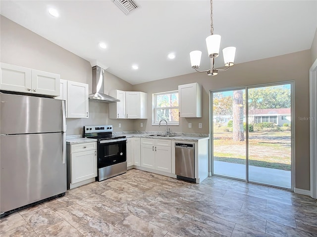 kitchen featuring appliances with stainless steel finishes, hanging light fixtures, wall chimney exhaust hood, sink, and white cabinetry