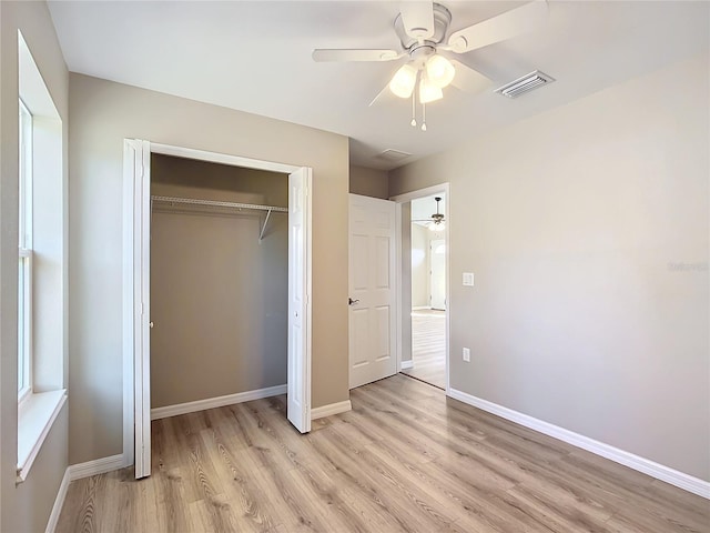 unfurnished bedroom with ceiling fan, light hardwood / wood-style flooring, and a closet