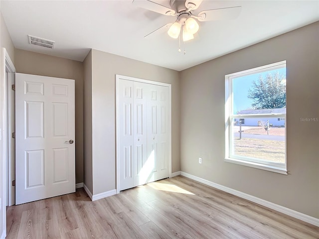 unfurnished bedroom with multiple windows, a closet, ceiling fan, and light hardwood / wood-style flooring