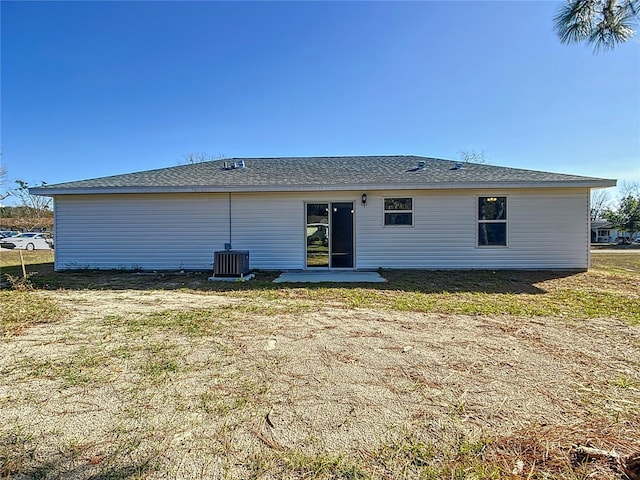 back of house with central air condition unit and a yard