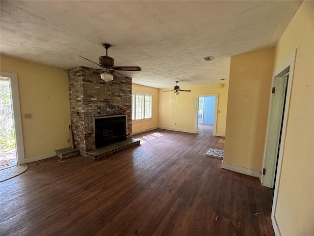 unfurnished living room with a textured ceiling, ceiling fan, dark hardwood / wood-style flooring, and a fireplace