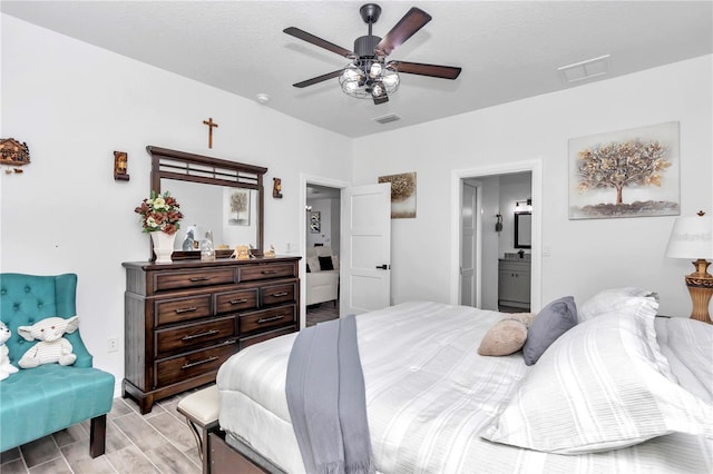 bedroom with ceiling fan, wood finish floors, ensuite bath, and visible vents