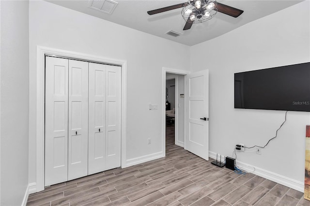 unfurnished bedroom featuring baseboards, visible vents, a closet, and wood finish floors