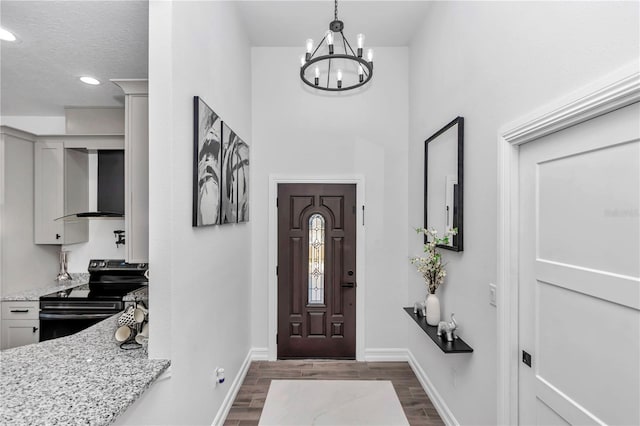 entrance foyer with a chandelier, recessed lighting, dark wood finished floors, and baseboards