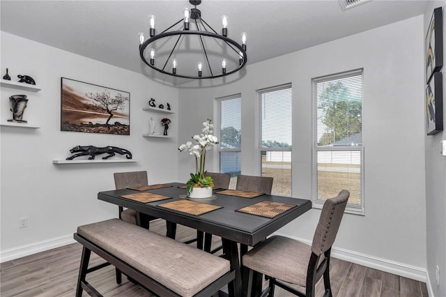 dining area with baseboards, wood finished floors, and an inviting chandelier