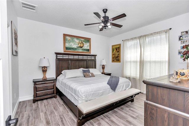 bedroom featuring a ceiling fan, wood finish floors, visible vents, and baseboards