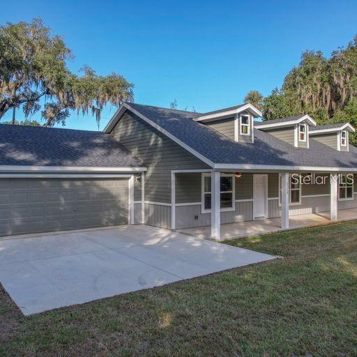 view of front of house with a garage, a front lawn, and covered porch