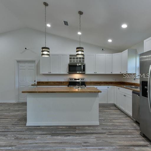 kitchen with white cabinets, pendant lighting, stainless steel appliances, and a center island with sink