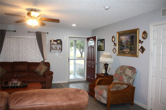 living room with a textured ceiling, ceiling fan, and wood-type flooring