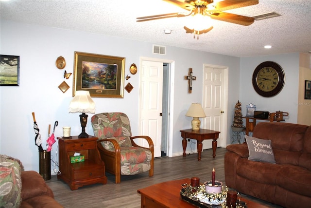 living room featuring wood-type flooring, a textured ceiling, and ceiling fan