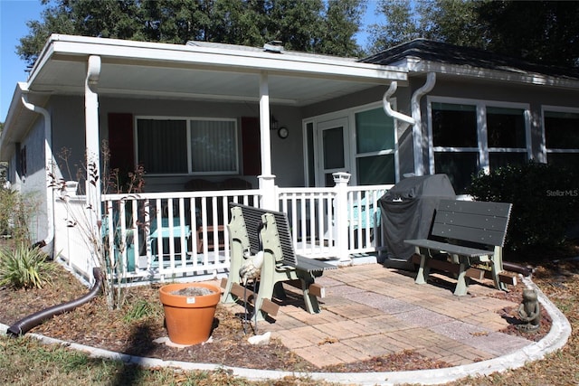 rear view of property featuring a porch and a patio area