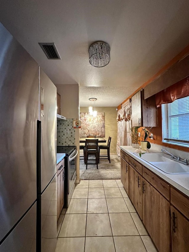 kitchen featuring sink, light tile patterned flooring, hanging light fixtures, stainless steel appliances, and a chandelier