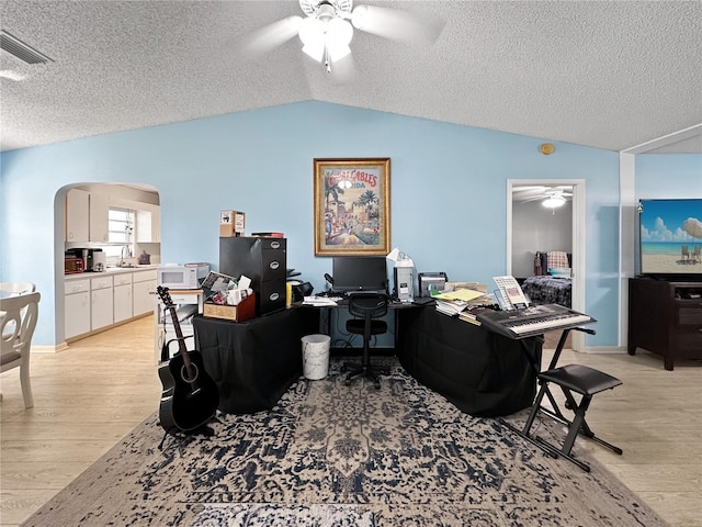 office space with vaulted ceiling, ceiling fan, a textured ceiling, and light hardwood / wood-style floors