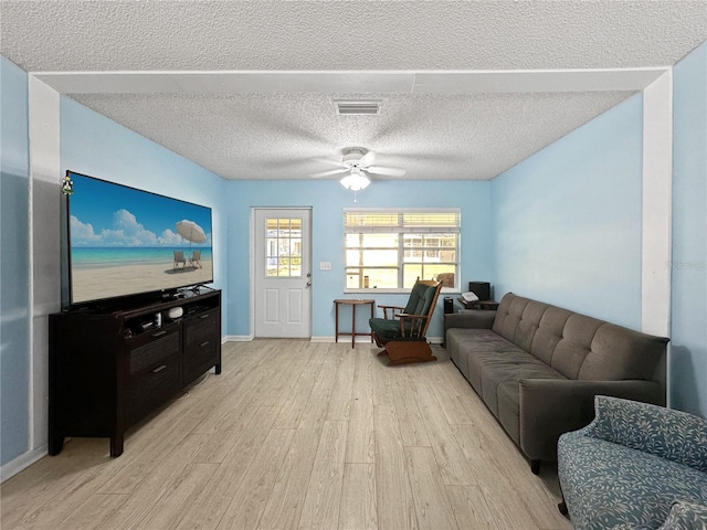 living room with light wood-type flooring, ceiling fan, and a textured ceiling