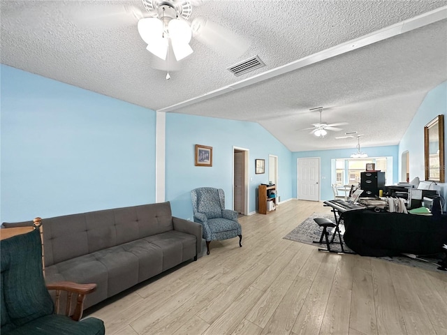 living room with a textured ceiling, ceiling fan, vaulted ceiling, and light wood-type flooring